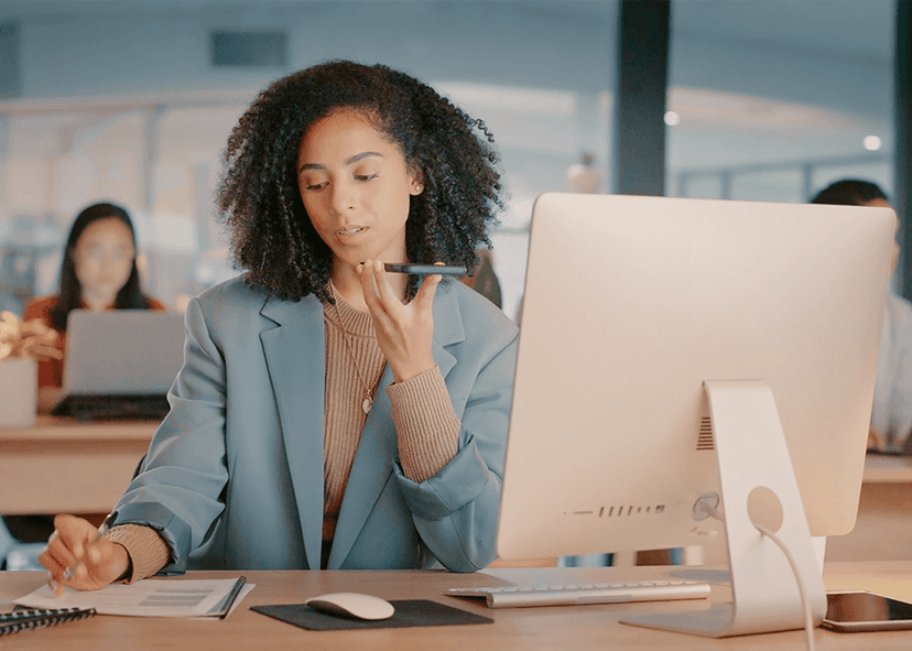 Woman in office talking to smartphone at desk